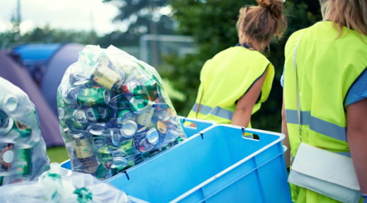 Two workers pulling bins of recycling