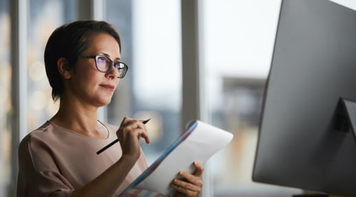 Woman with clipboard looking at computer monitor